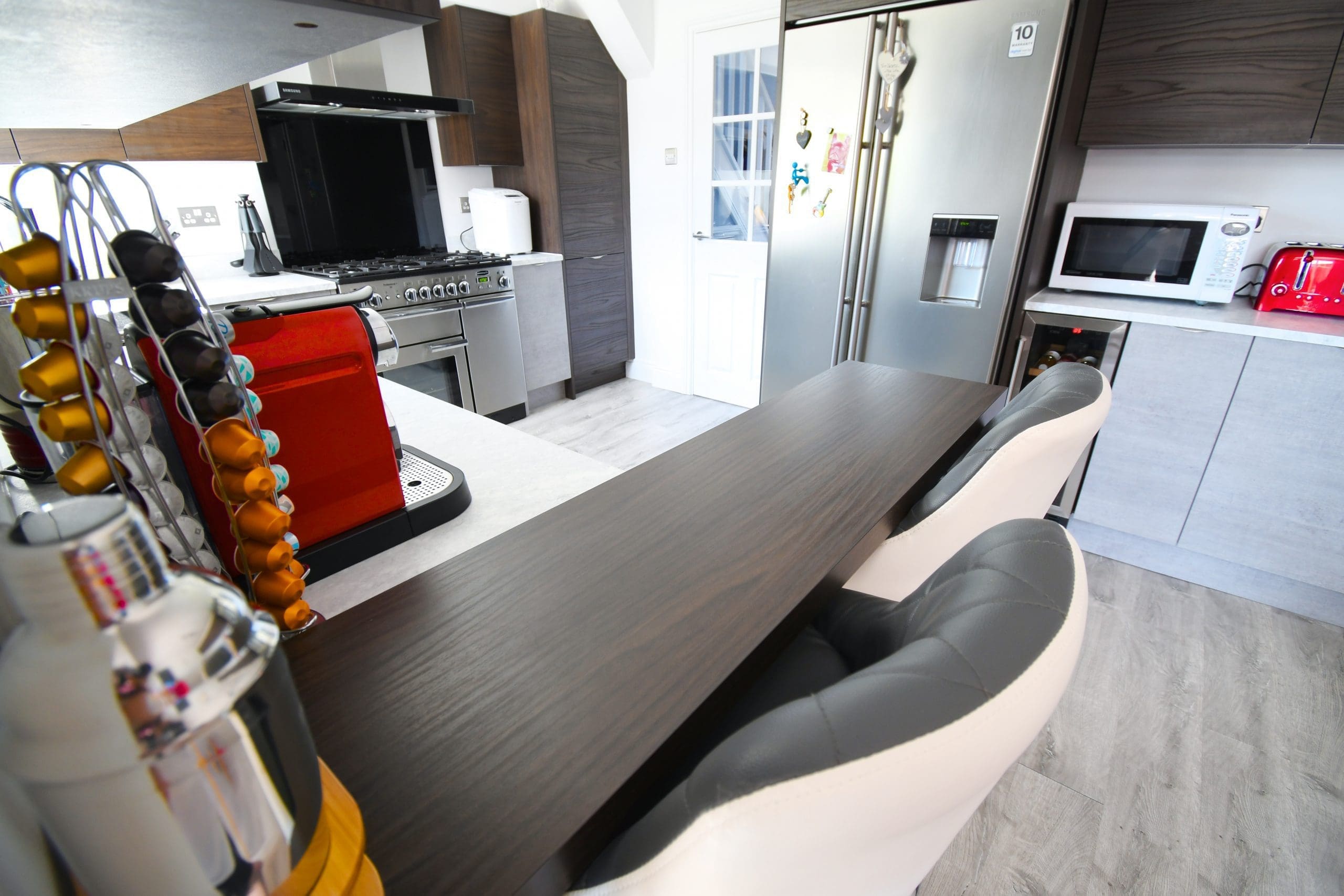 Two Tone Concrete and Dark Walnut Handle-less and Slab Kitchen, with Walnut 38mm Breakfast Bar and Minerva Solid Surface Worktops Stonemill Kitchens