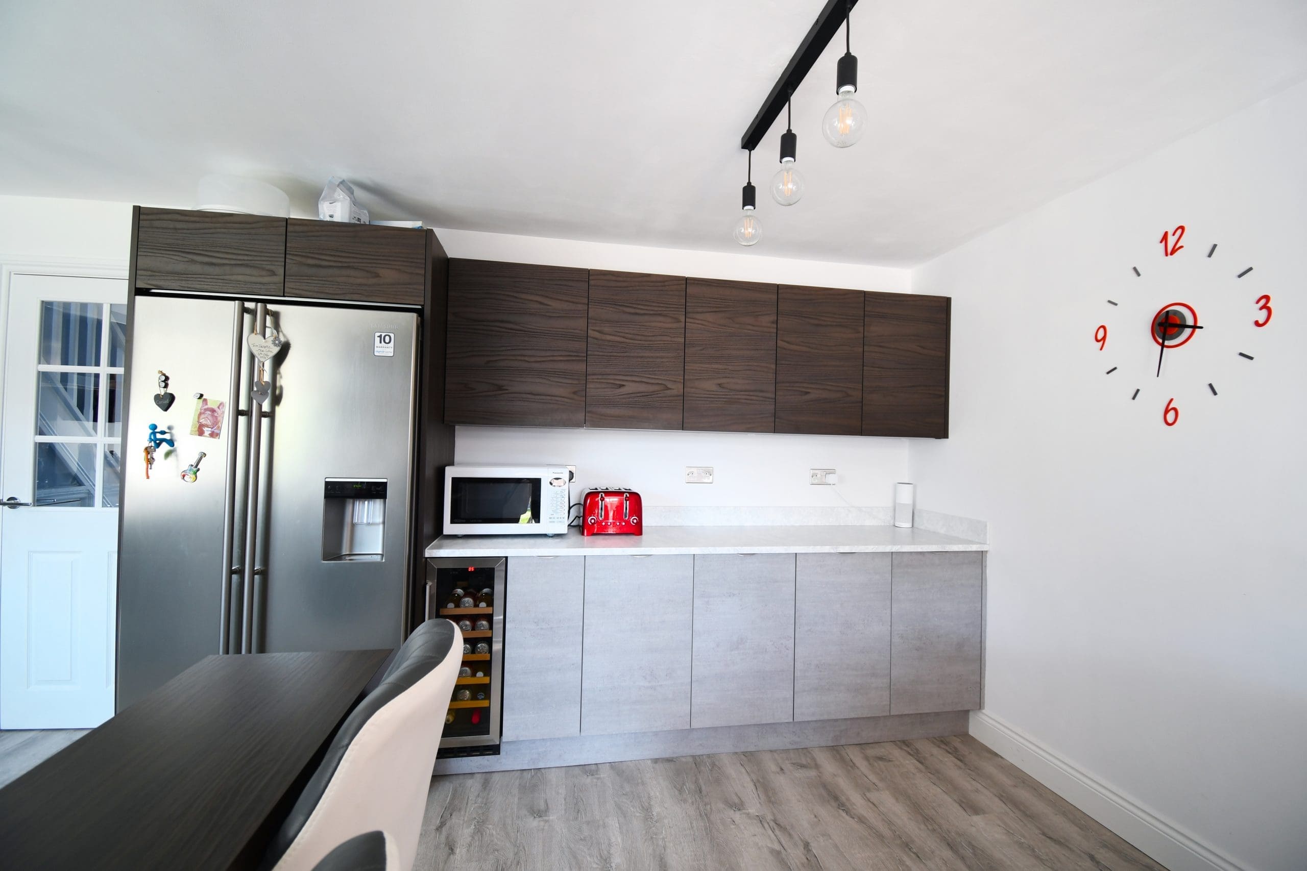 Two Tone Concrete and Dark Walnut Handle-less and Slab Kitchen, and Minerva Solid Surface Worktops and Dark Walnut chunky breakfast bar and Samsung American Fridge Freezer Stonemill Kitchens