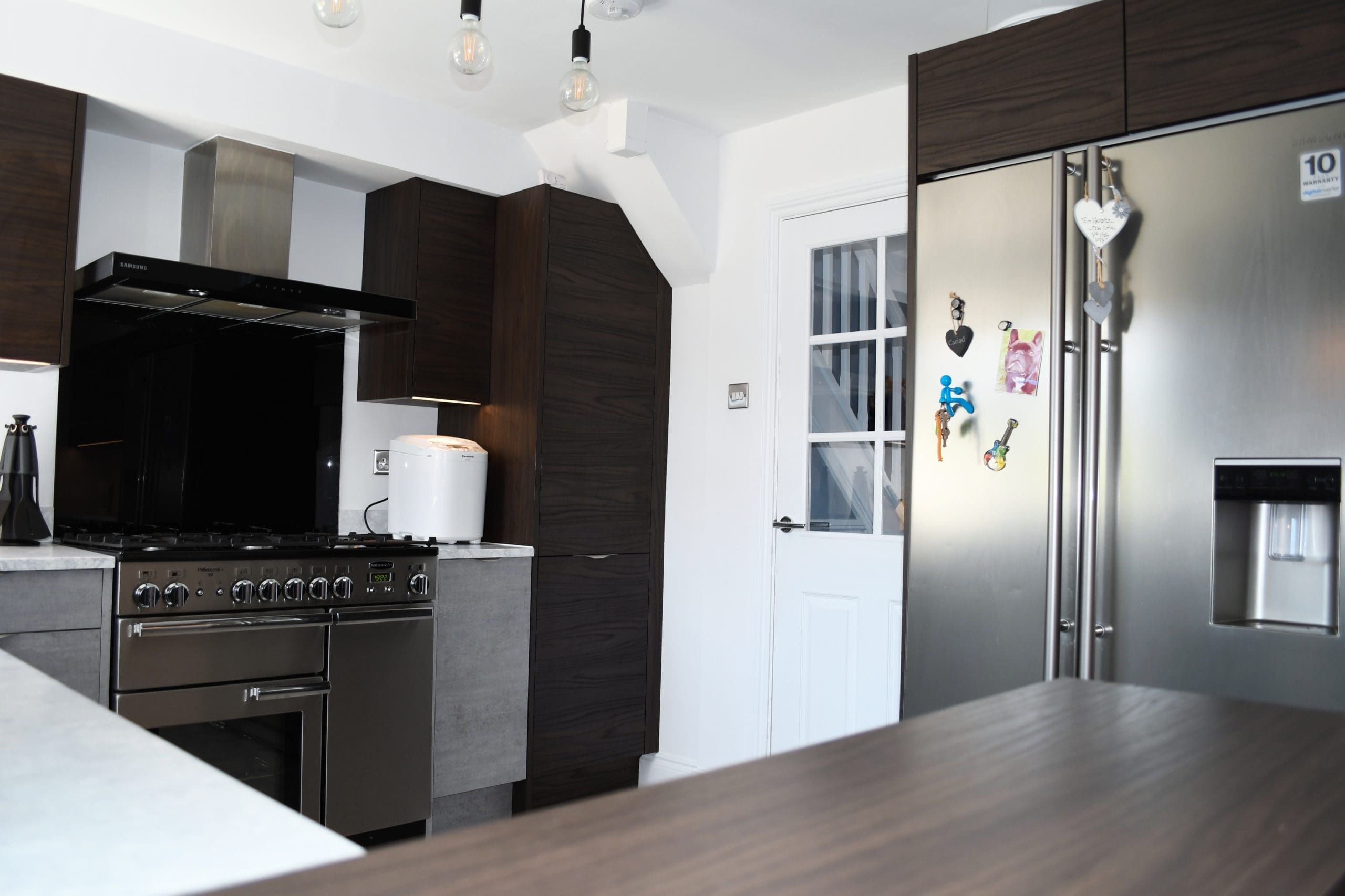 Two Tone Concrete and Dark Walnut Handle-less and Slab Kitchen Rangemaster Oven Samsung Extractor Fan and American Fridge Freezer with Minerva Solid Surface Worktops Stonemill Kitchens