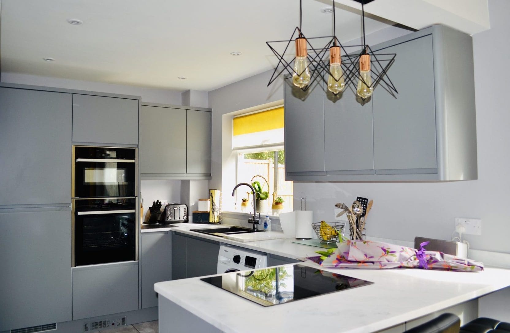 Dust Grey J Handle Kitchen with curved end posts and white worktops.
