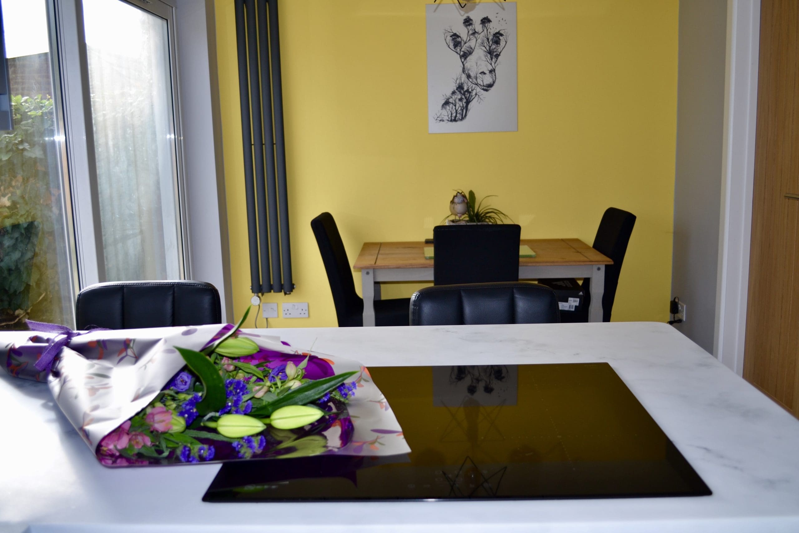 Dust Grey J Handle Kitchen with white worktops, neff hob in the center with picture of flowers on worktop
