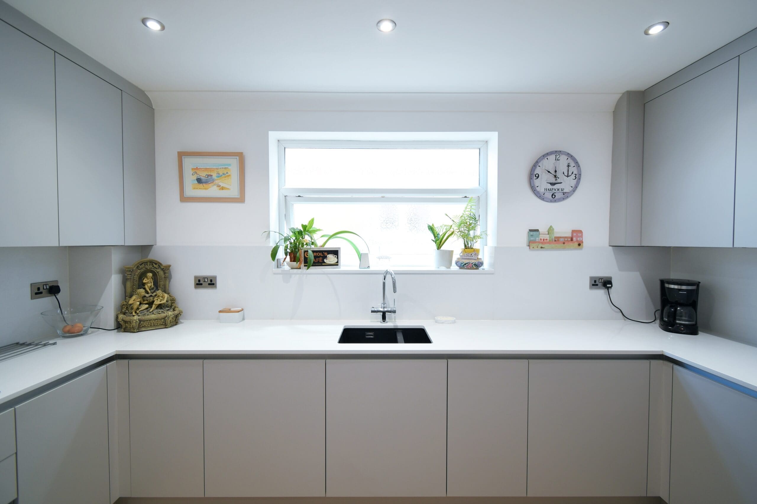 Light Grey sleek Handleless kitchen with sink in the center with a Quooker boiling water tap