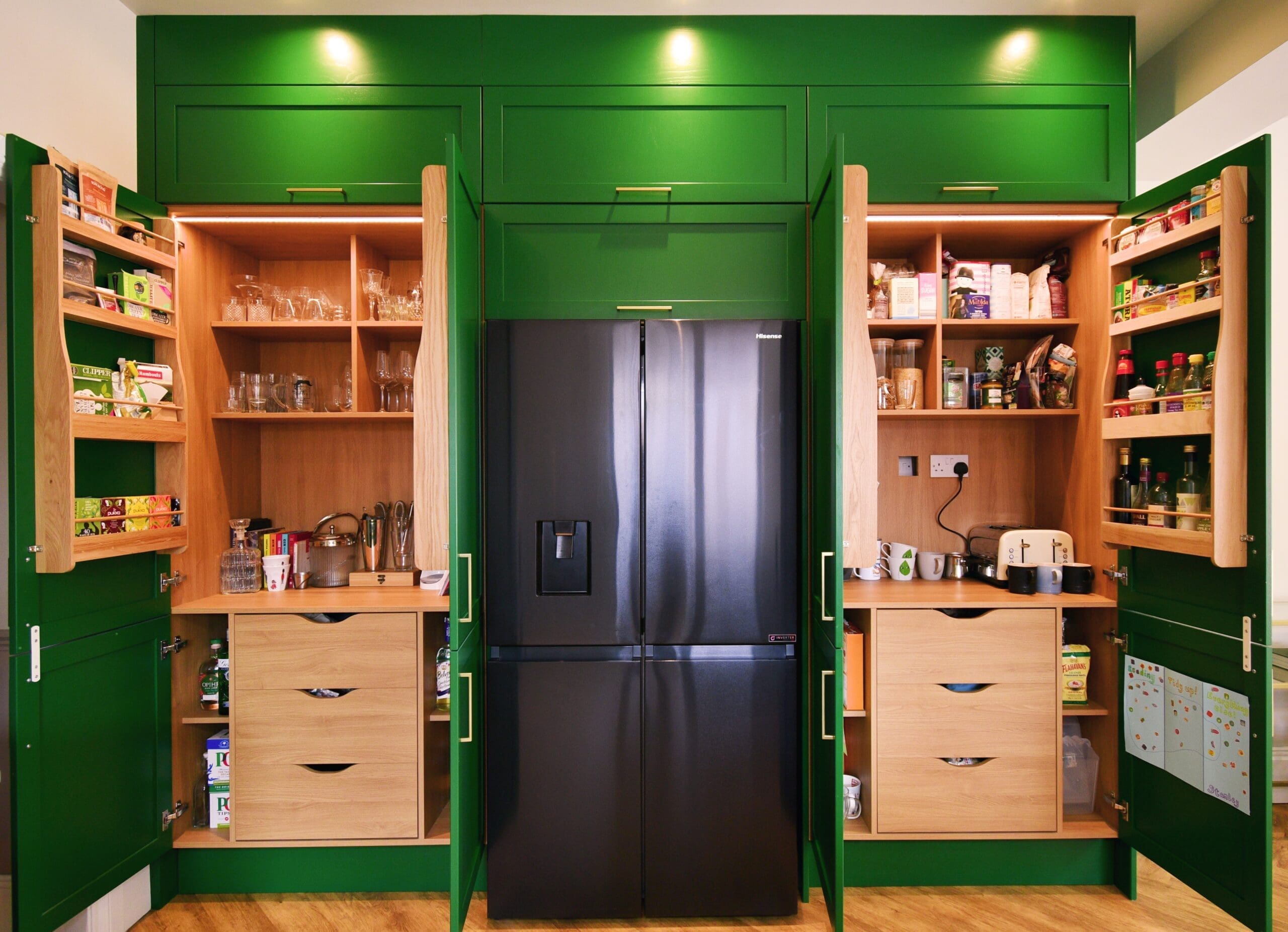Green shaker kitchen with bright white quartz surfaces and a sleek larder pantry